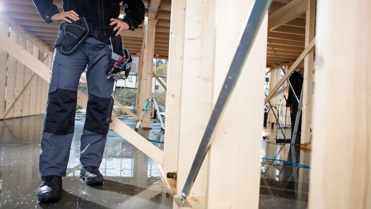 © Tyler Olson - stock.adobe.com Low section of carpenter standing with hands on hips at construction site