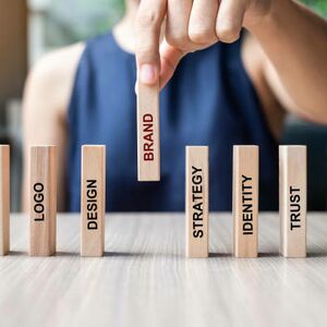 Businesswoman hand placing or pulling wooden Dominoes with BRAND text. and Marketing, Advertising, Logo, Design, Strategy, Identity, Trust and Values. Product development concept