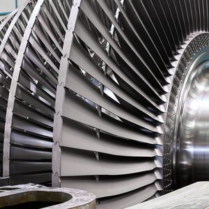 Rotor with blades of contemporary powerful steam turbine in brightly lit workshop of equipment production plant close view