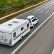 Pkw mit Wohnwagen als Anhänger fährt auf der Straße
