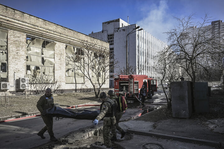 EDITORS NOTE: Graphic content / Military emergency service members remove the body of a dead Ukrainian serviceman in the area of a research institute, part of Ukraine's National Academy of Science, after a strike, in northwestern Kyiv, on March 22, 2022. - Russians reinforce their positions around the capital which has not yet been fully surrounded on the 27th day of the assault. (Photo by Aris Messinis / AFP)