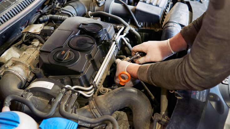 Ein Mechaniker arbeitet an einem Verbrennungsmotor. Der Verbrenner ist ab 2035 bei Pkw nicht mehr erlaubt.