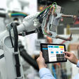 Engineer hand using tablet, heavy automation robot arm machine in smart factory industrial with tablet real time monitoring system application. Industry 4th iot concept.