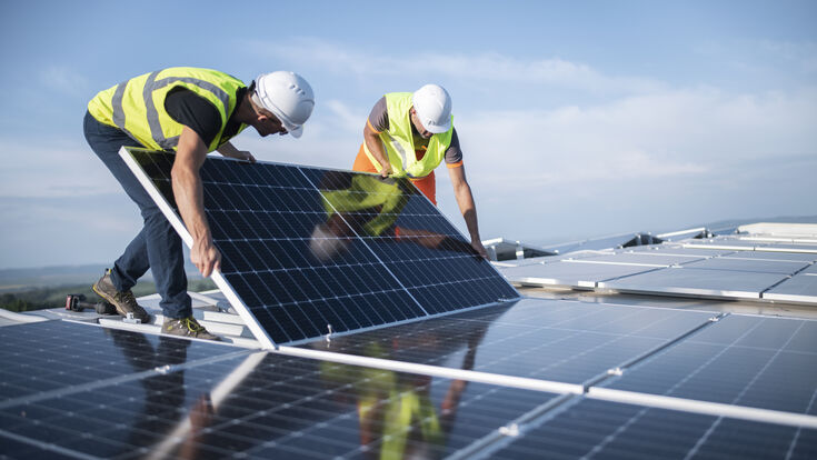 © Getty Images Team of two engineers installing solar panels on roof.