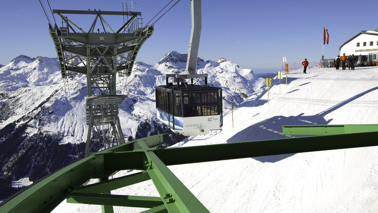 Lech, Austria - February 07, 2011: The Rufibahn cable car descending from the Rufikopf Bergstation. Skiers are looking at the cable car and surrounding views. Lech is a well known ski resort in the Austrian Alps.