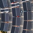 Aerial view directly above electric cars parking under solar panels on a parking lot rooftop ready for charging