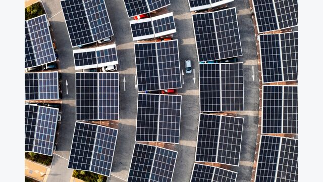 Aerial view directly above electric cars parking under solar panels on a parking lot rooftop ready for charging