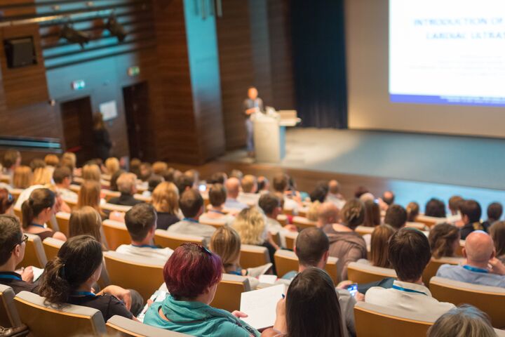Speaker giving a talk on scientific conference. Audience at the conference hall. Business and Entrepreneurship concept.