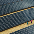Luftansicht auf riesige Photovoltaikanlage mit zwei Menschen daneben