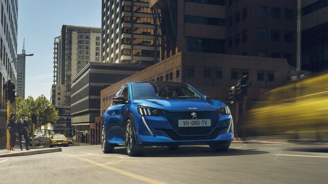 Peugeot auf einer Straße mit modernen Hochhäusern im Hintergrund