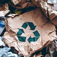 A pile of assorted paper and cardboard materials marked with the universal recycling symbol, set against a neutral background to promote environmental conservation and sustainable practices.