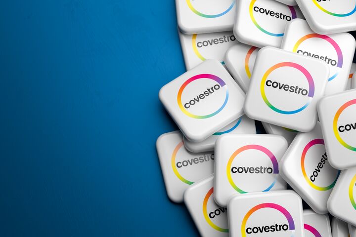 Logos of the German producer of polyurethane and polycarbonate Covestro on a heap on a table. Copy space. Web banner format.