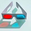 close up of a fun 3d glasses made with cardboard and plastic to create cheap tree optical perception by eyes seeing films at cinema.The glasses have two lens in red and blue colors on blue background
