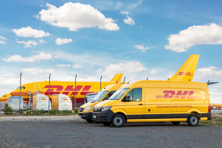 Schkeuditz, Germany - 29th May, 2022 - Many courier van against cargo planes parked on Leipzig Halle airport terminal apron for loading distribution. DHL air mail express fast logistic hub terminal.