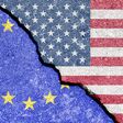 © Eugene_Photo - stock.adobe.com The crack between the flags of the United States and the European Union. The concept of problems in the relations of countries, trade tariffs and disagreements.