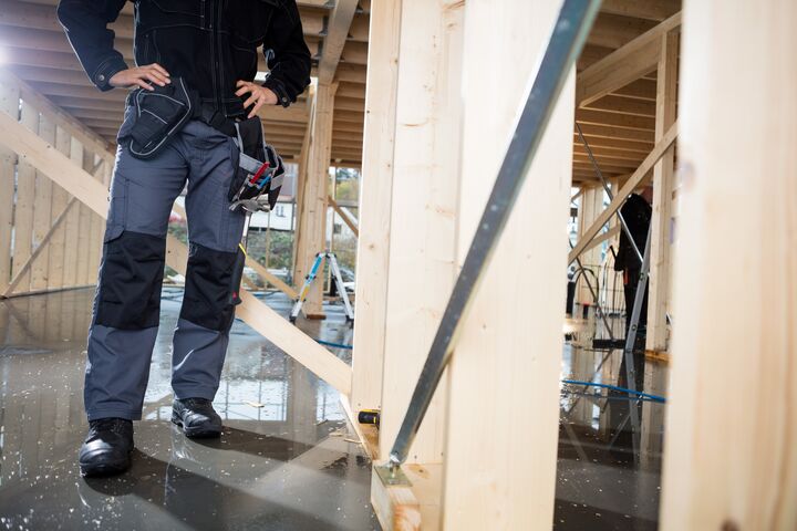 Low section of carpenter standing with hands on hips at construction site