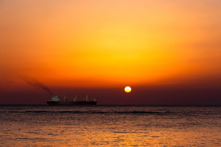 A silhouette of a cargo ship at sunset.