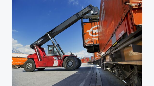 Fahrzeug hebt Gebrüder-Weiss-Container von Zug
