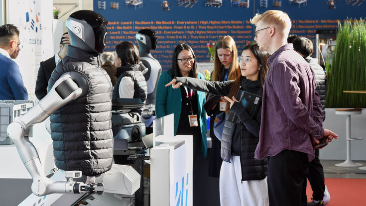 Logimat-Besucherin zeigt auf humanoiden Roboter