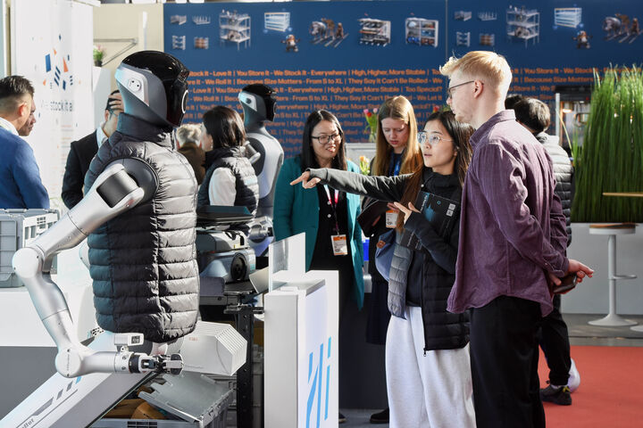 Logimat-Besucherin zeigt auf humanoiden Roboter