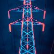 High voltage power line tower illuminated in neon colors against a dark stormy sky, showcasing modern energy infrastructure.