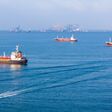 LPG gas and oil tanker ships anchored in the ocean, with a fast patrol boat in the foreground. Global energy transport, war energy crisis, and Strait of Hormuz blockade concept.