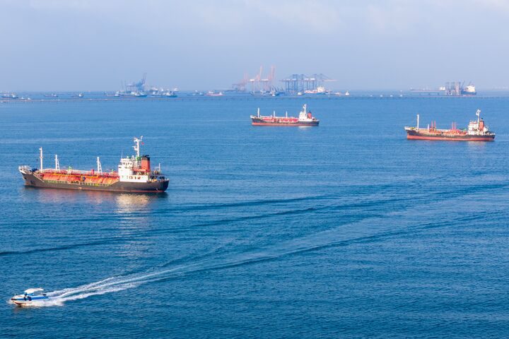LPG gas and oil tanker ships anchored in the ocean, with a fast patrol boat in the foreground. Global energy transport, war energy crisis, and Strait of Hormuz blockade concept.