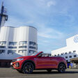 Rotes Volkswagen-Cabrio vor dem VW-Werk Osnabrück mit sichtbarem Volkswagen-Logo am Gebäude.