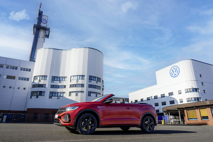Rotes Volkswagen-Cabrio vor dem VW-Werk Osnabrück mit sichtbarem Volkswagen-Logo am Gebäude.