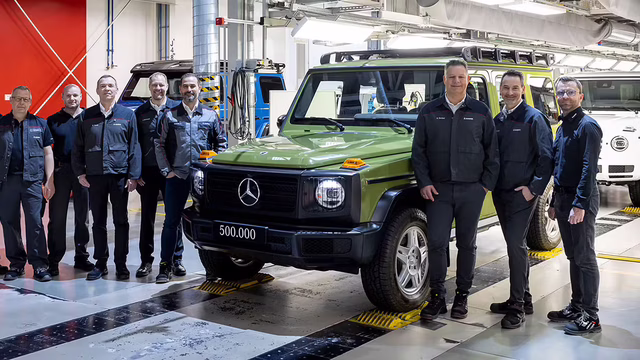 Mehrere Mitarbeiter stehen in einer Produktionshalle neben einer grünen Mercedes-Benz G-Klasse mit der Aufschrift 500.000.