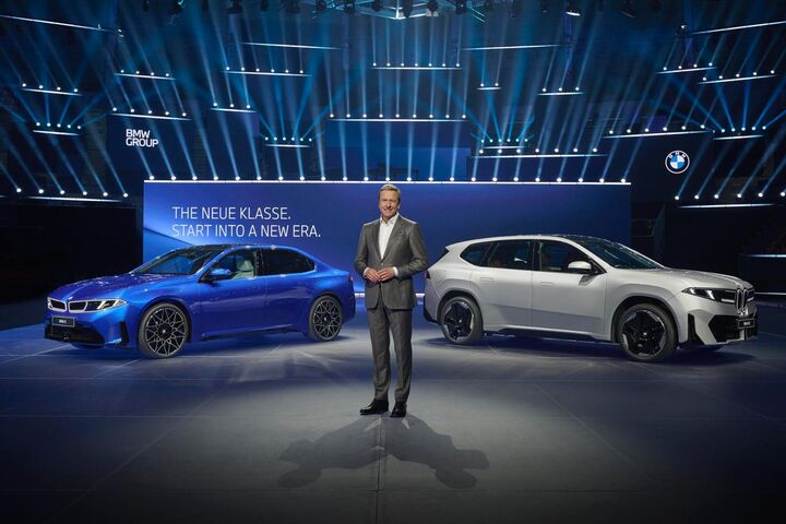 BMW präsentiert die Neue Klasse auf einer Bühne mit zwei Elektroautos, darunter ein weißer BMW iX3, vor großem Schriftzug „The Neue Klasse. Start into a new era“.