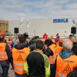 Beschäftigte mit IG-Metall-Westen vor einem Mahle-Werk mit sichtbarem Firmenlogo.