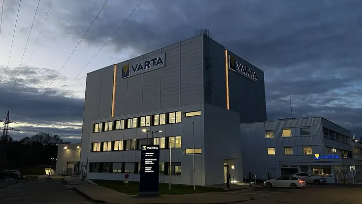 Varta-Werk mit beleuchtetem Logo bei dunklem Himmel