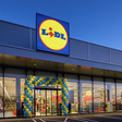 Lidl-Filiale mit beleuchtetem Lidl-Logo und Eingang im Abendlicht.