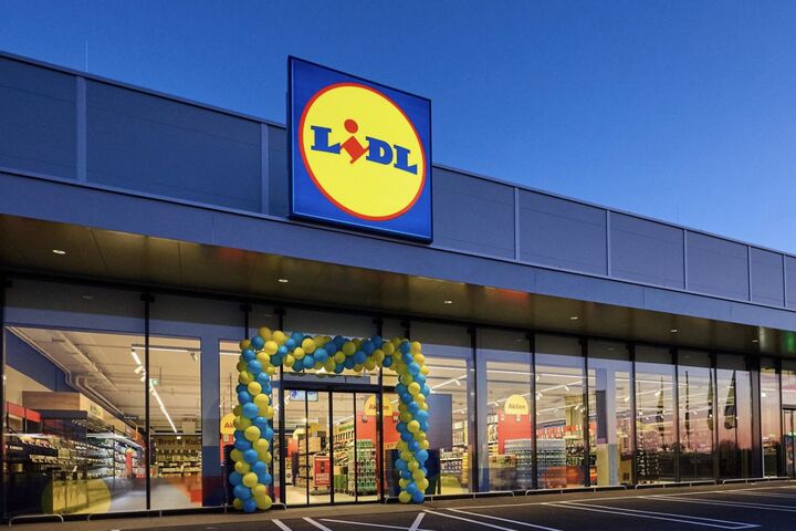 Lidl-Filiale mit beleuchtetem Lidl-Logo und Eingang im Abendlicht.