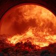 Extreme heat and fiery combustion within a industrial rotary kiln, showcasing molten material and intense flames