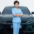 Stella Li vor einem dunkelblauen BYD