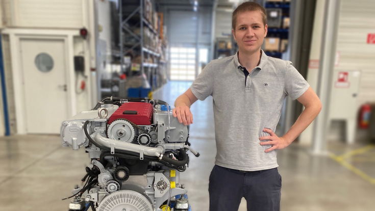 Mitarbeiter von Steyr Motors steht neben einem Hochleistungsmotor in einer Werkhalle