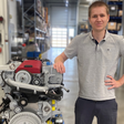 Mitarbeiter von Steyr Motors steht neben einem Hochleistungsmotor in einer Werkhalle