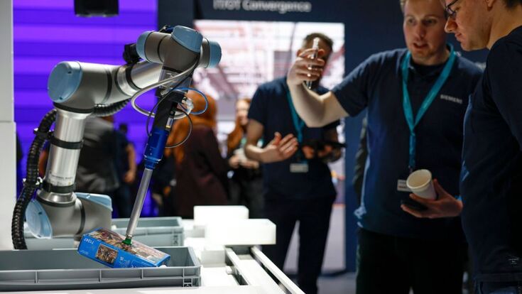Roboterarm auf einem Siemens-Stand: Industrielle KI, Automatisierung und Engineering rücken durch neue KI-Modelle wie OpenAI, DeepSeek und Mistral stärker zusammen.