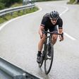 Road cyclist descending sharp mountain curve in performance gear speed endurance training racing concept on winding alpine asphalt with focus determination motion or fitness challenge