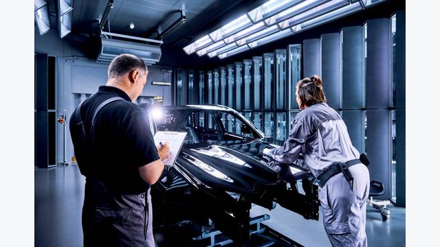 Mitarbeiter von Mercedes Benz bei der Montage eines PKW in einer Montagehalle