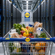 Ein Supermarktgang, in dem die Regale nicht mit Lebensmitteln, sondern vollständig mit Servern bestückt sind – und ein einzelner Einkaufswagen fährt durch den Gang.