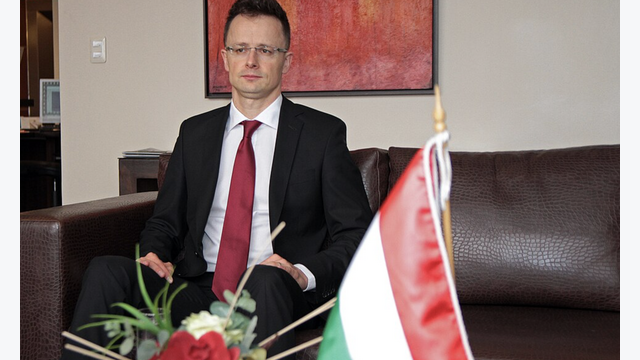 Péter Szijjártó vor einer Ungarn Flagge in einem Büro