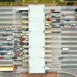 An overhead view of a busy toll road with many cars queuing up to pay the highway toll