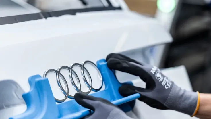Audi Ringe werden auf ein Fahrzeug montiert
