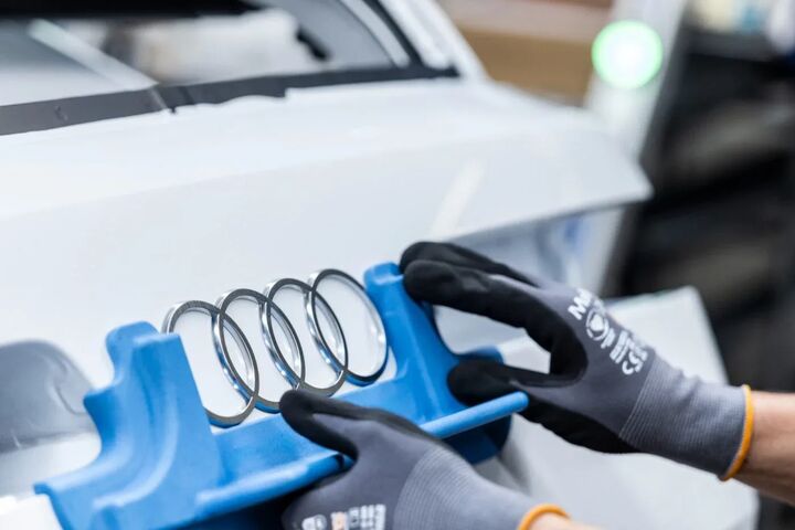 Audi Ringe werden auf ein Fahrzeug montiert