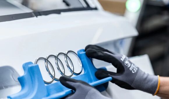 Audi Ringe werden auf ein Fahrzeug montiert