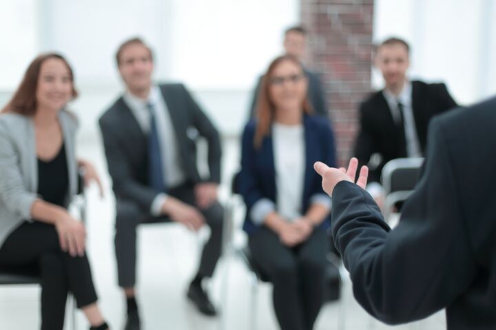 Der Coach in einem Seminar bringt einem Raum voller Geschäftsleute Kursinhalte näher.