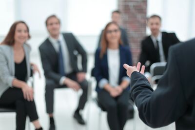 Der Coach in einem Seminar bringt einem Raum voller Geschäftsleute Kursinhalte näher.